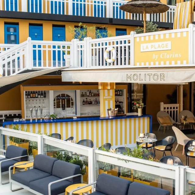 La terrasse de La Plage by Clarins, rayée de jaune, au bord du bassin